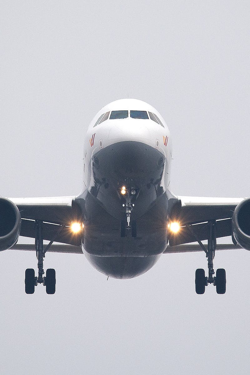 A commercial airliner captured head-on, preparing to land against a cloudy sky.